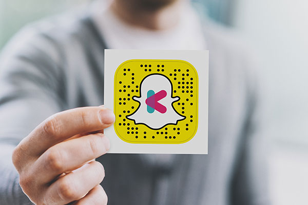 Man holing a vinyl kiss-cut sticker of a Snapchat QR code with a business logo.